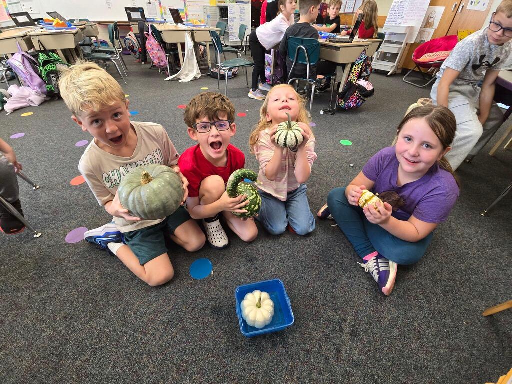 students holding pumpkins in classroom