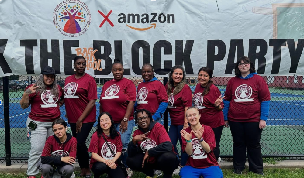 Amazon Volunteers are posing in front of the back to school block party banner 