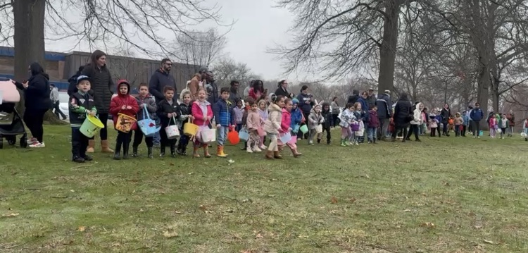 students holding their baskets about to participate in egg hunt outside  