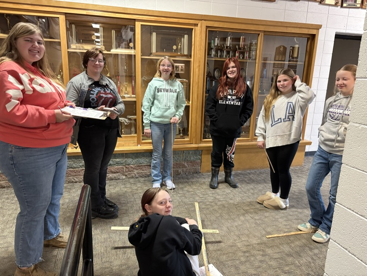 The 8th graders have been learning about indirect measurement. Using similar triangles they estimated the height of the glass trophy case above the gym door  