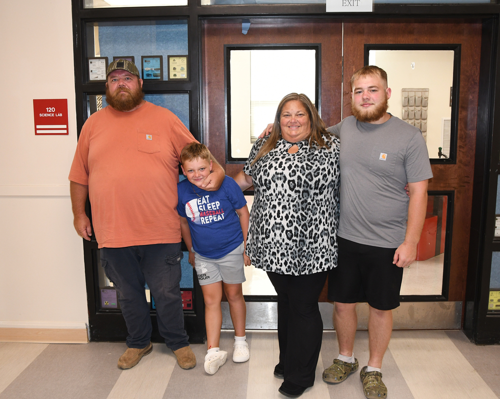 Four people stand in front of a door with glass panels. They are smiling for a photo.