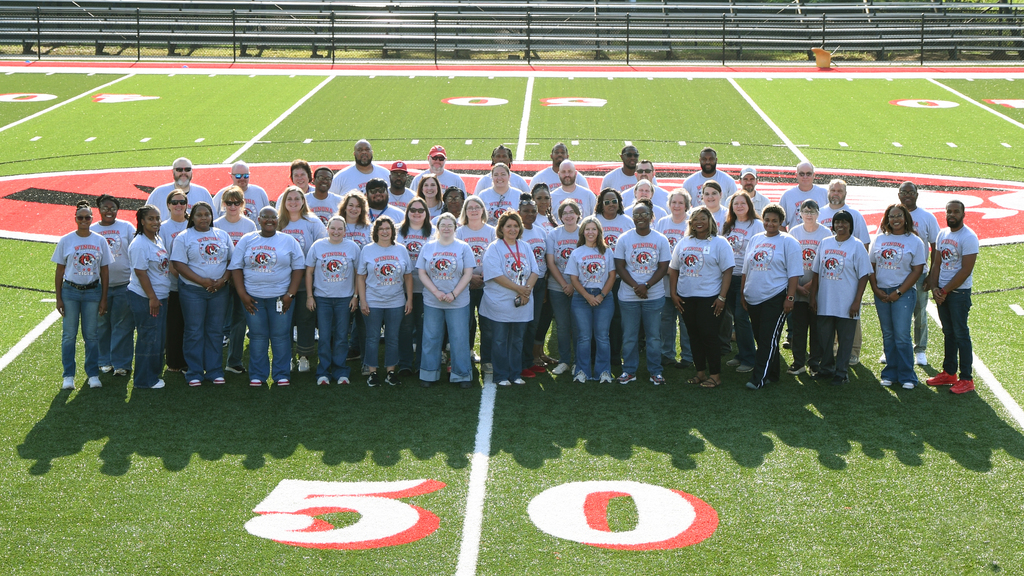 A group of people wearing white shirts and jeans standing on a field with numbers "50" on it.