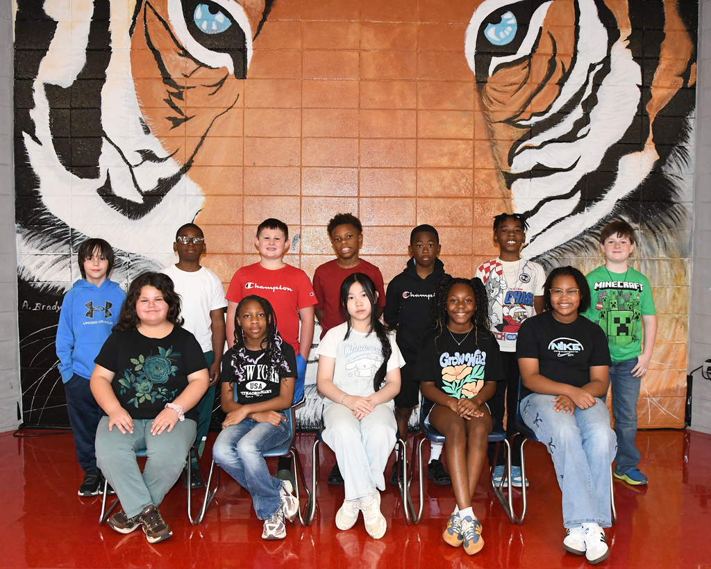 Group of students posing for a picture in front of a wall with a tiger mural.