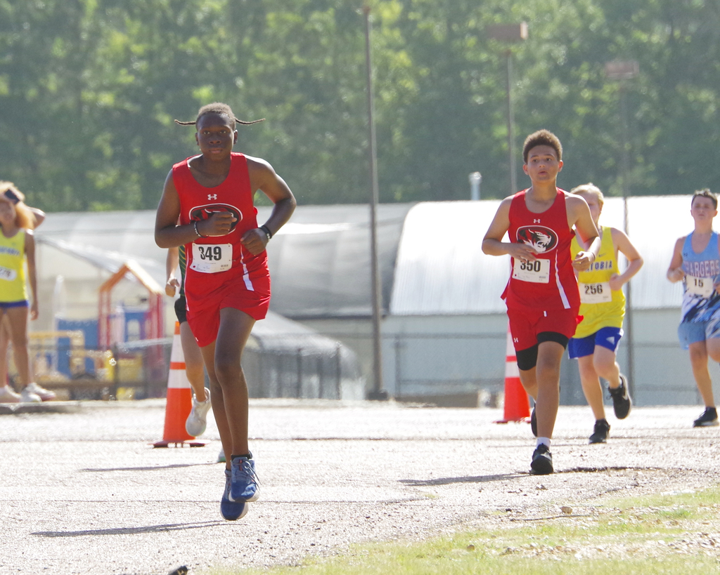 A group of runners compete in a race. A runner wears a red uniform and number 148.