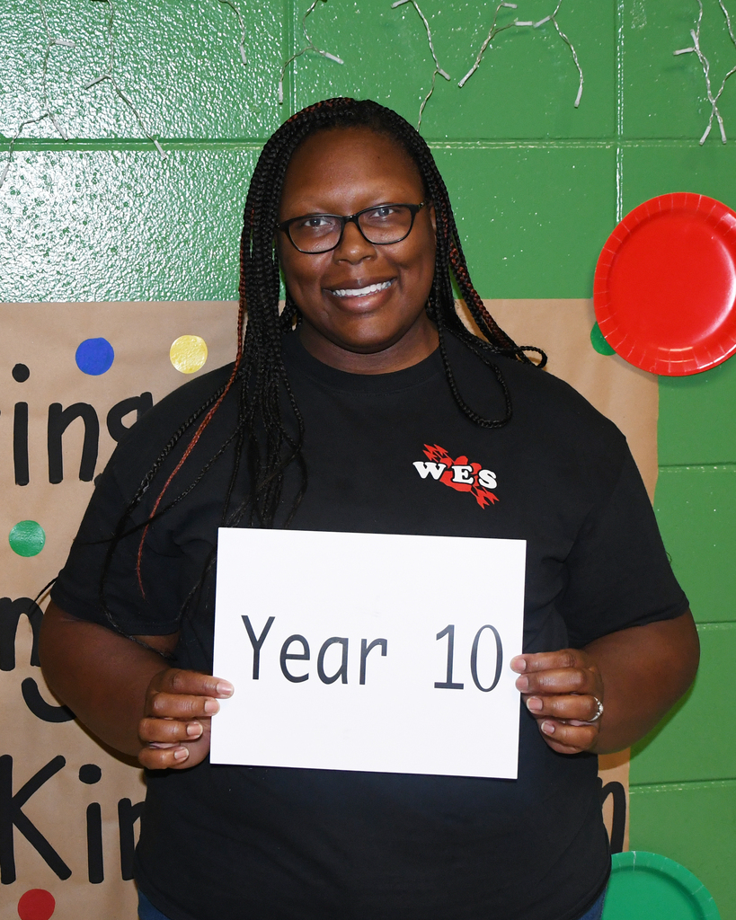 A person in a black shirt with "WES" and glasses stands holding a sign that reads "Year 10".