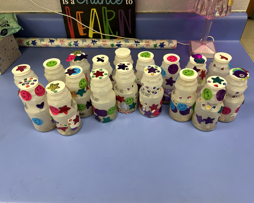 Decorated milk cartons arranged in a row on a blue surface with a sign in the background.