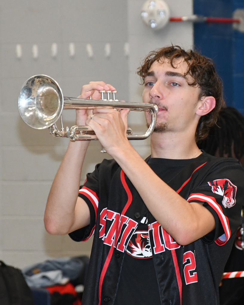 A person playing a trumpet, wearing a black baseball jersey with red and white accents, and the number 2.