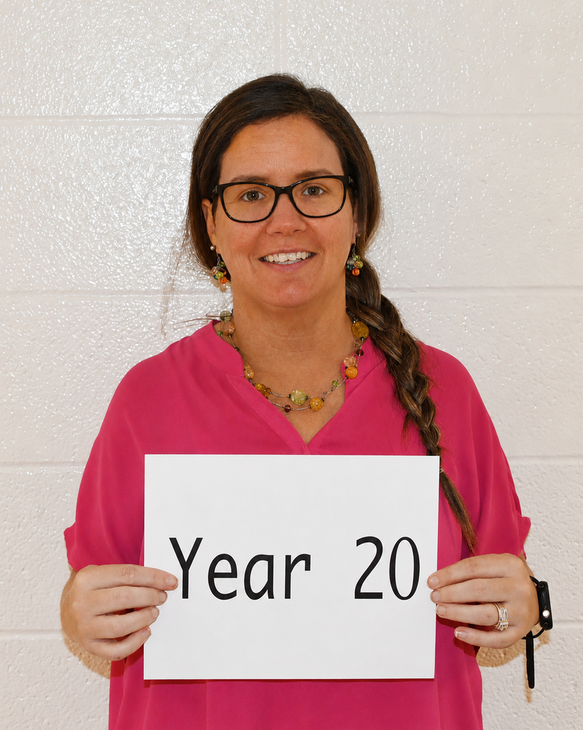 Woman wearing a pink top and glasses holds a white sign reading "Year 20" against a plain white background.