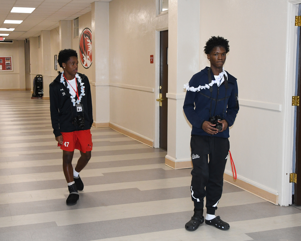 two boys walking down the hall with cameras