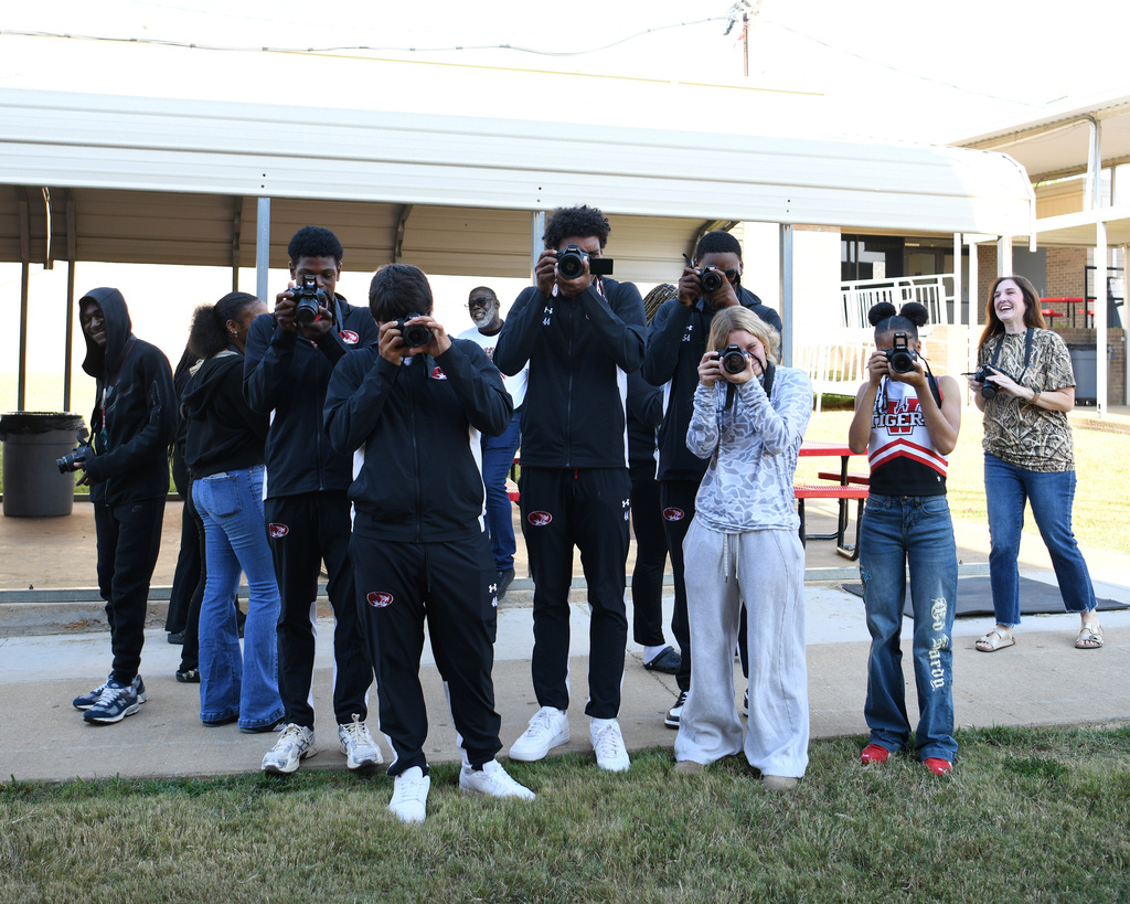A group of people with cameras pose for a photo in front of a building.