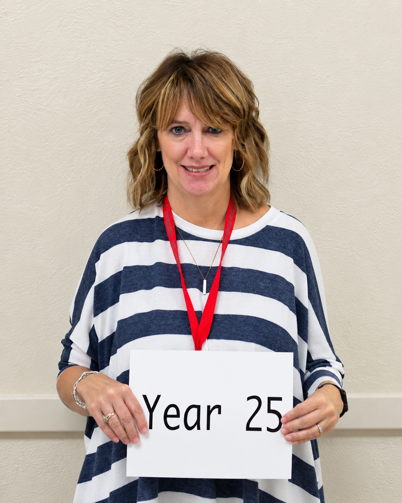 Person smiling, holding a sign with "Year 25" on it, wearing a blue and white striped shirt.