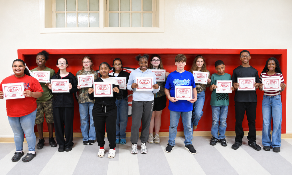A group of individuals holding white certificates in front of a red wall, standing on a tiled floor.