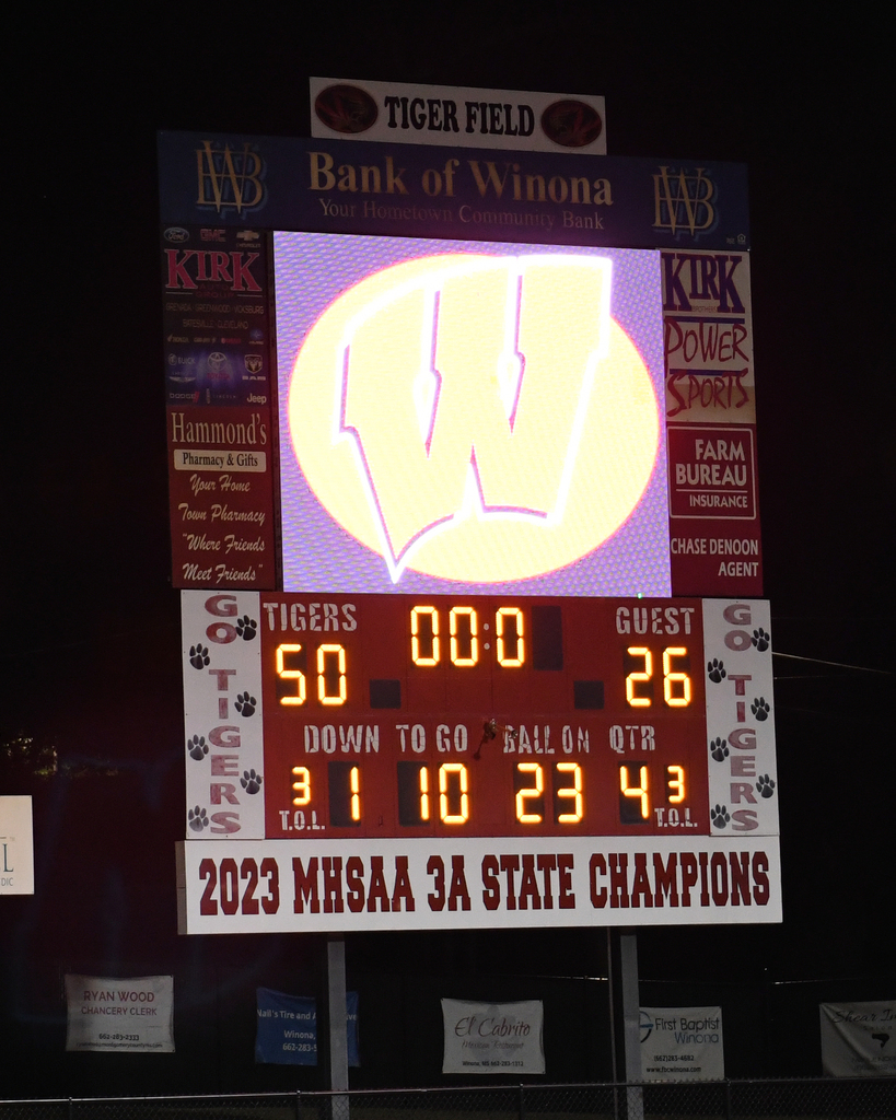 Scoreboard displaying "Tigers 50, Guest 26" with a glowing W logo, down to go, and ball clock. Banners in the background.