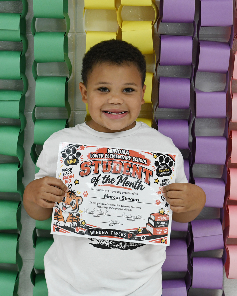 Boy holds a certificate for "Student of the Month" against a colorful background of multicolored paper circles.