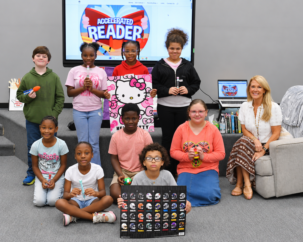 A group of children and adults gather in a room, smiling and posing for a photo.