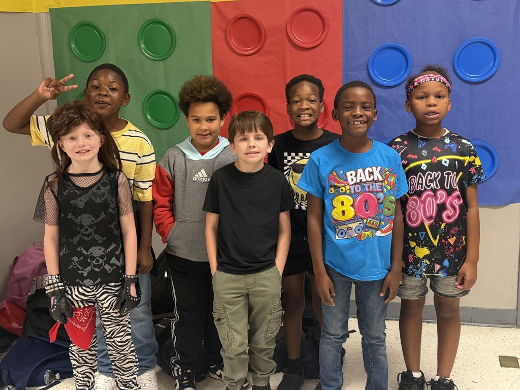 A group of children stands next to each other in front of a colorful backdrop.