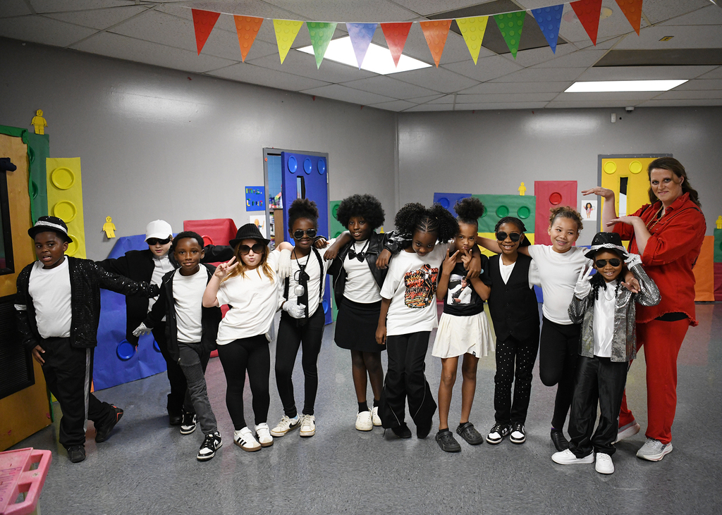 A group of children in matching outfits pose for a photo in a colorful playroom.