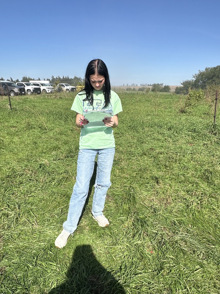 Student standing in a field studying Land Judging papers