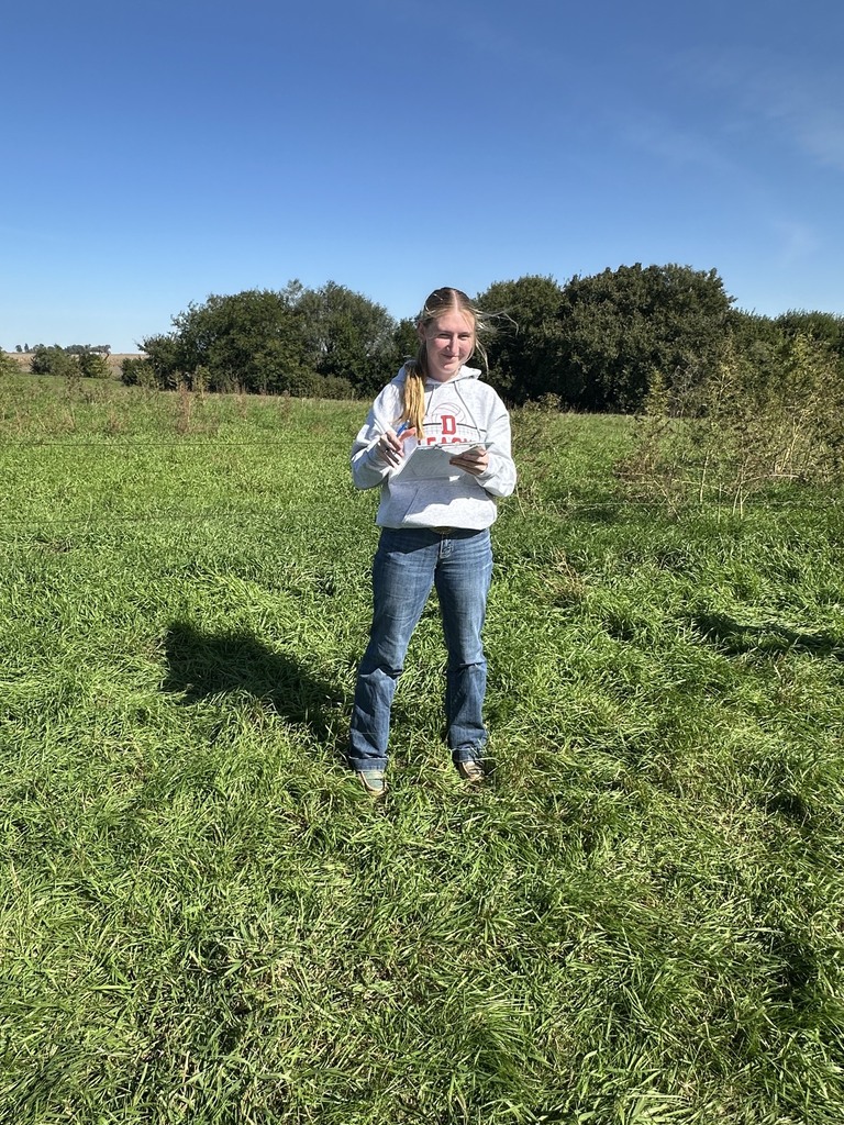Student standing in a field studying Land Judging papers