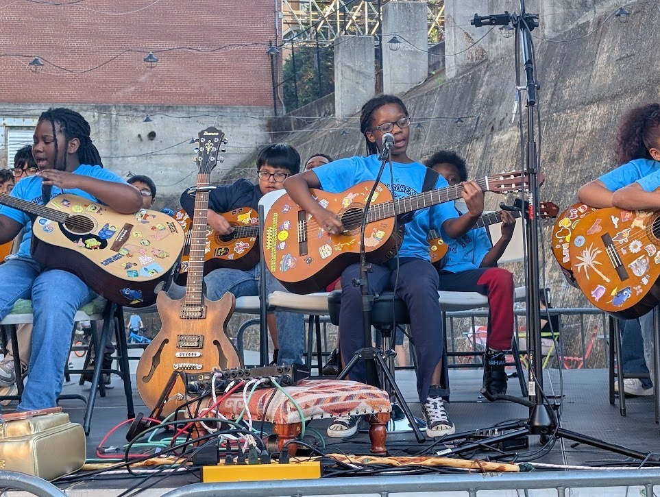 Children playing guitar and singing on stage