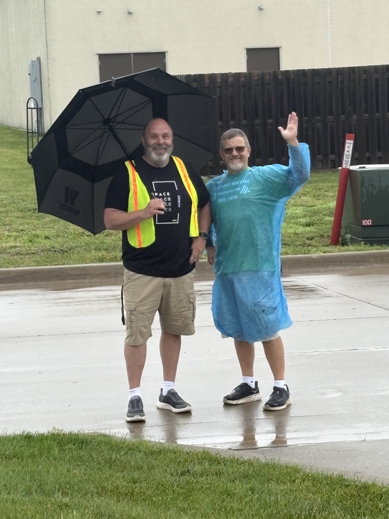 Staff waves while holding an umbrella in the rain