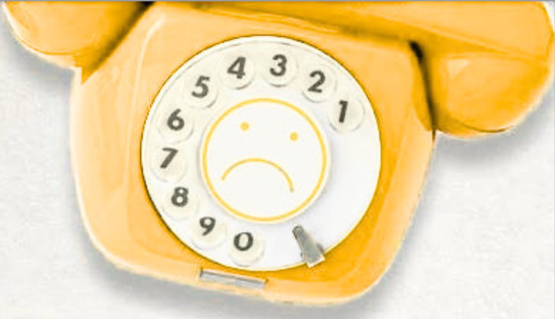 Yellow rotary phone with a sad face depicted on the dial, surrounded by numbers 1 to 9.