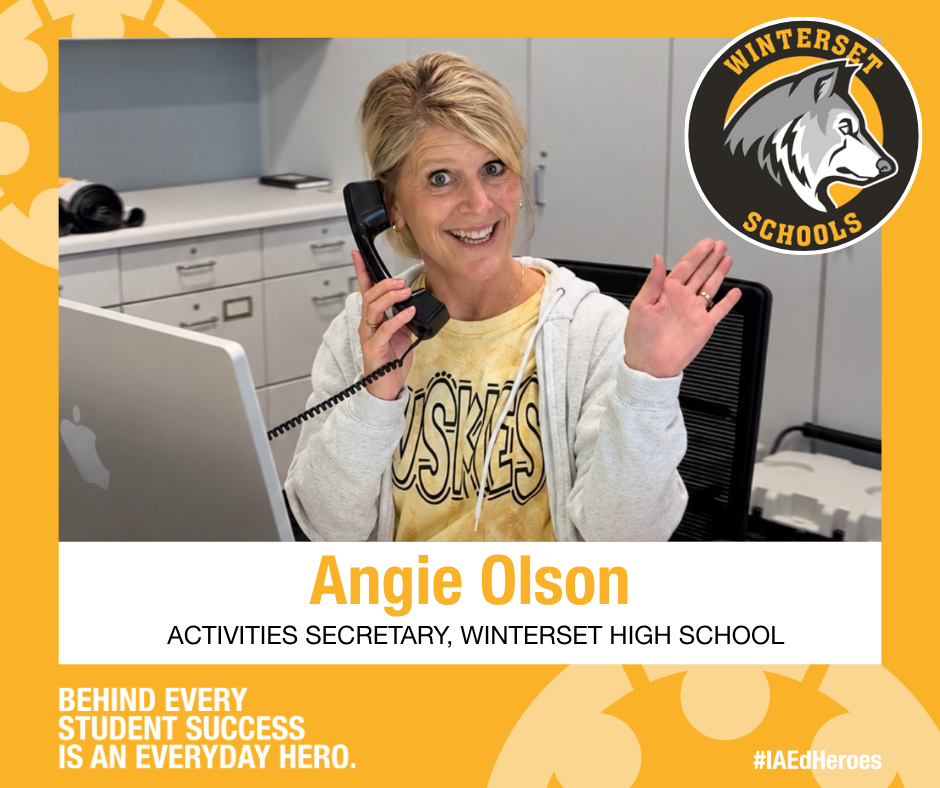 A smiling woman, Angie Olson, holds a phone and gestures. She wears a yellow shirt and a white jacket. Behind her is a desk with a computer, and a wolf logo appears in the background.