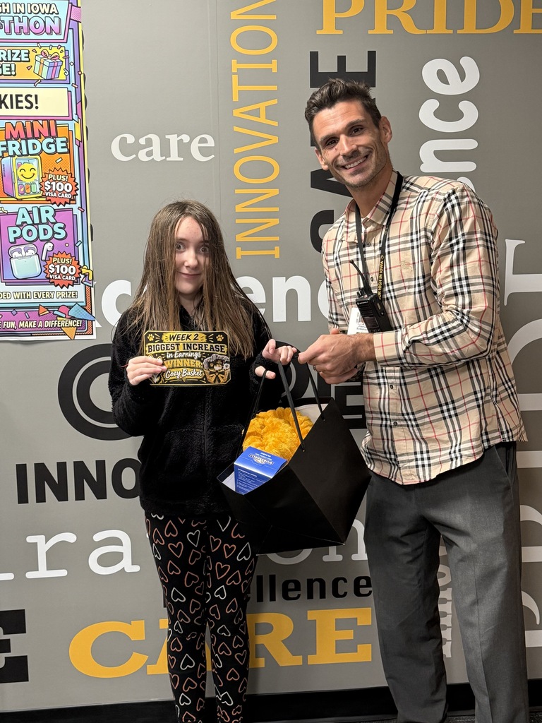 A young girl holds a yellow prize bag and a certificate while a man stands beside her.