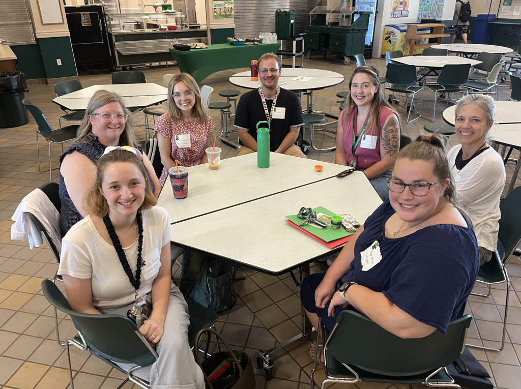 PICTURE OF 7 ADULTS SITTING AROUND A LUNCH TABLE