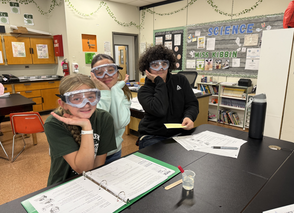 3 students wearing goggles pose for a picture