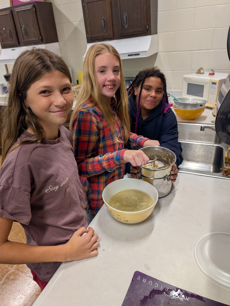 3 students using an apple mill to create sauce