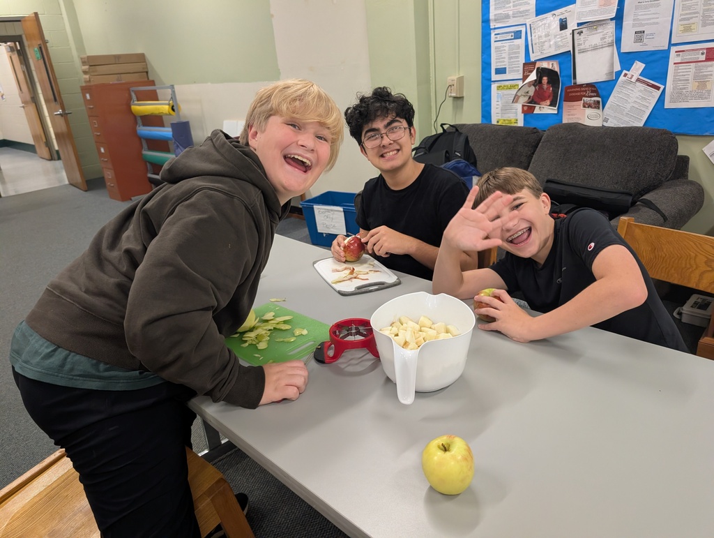 3 students slcing apples to make apple sauce