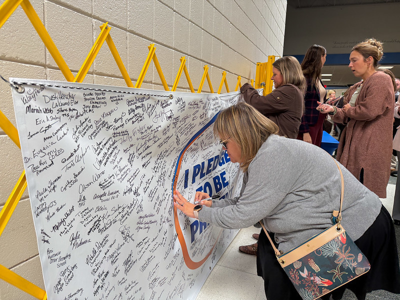 Amanda and Taylor signing the I Pledge to be Present banner