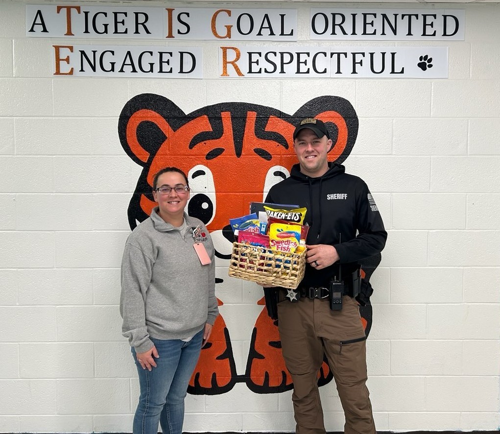 Photo of Ashley Romine handing Roman Rader a basket of goodies for Law Enforcement Appreciation Day
