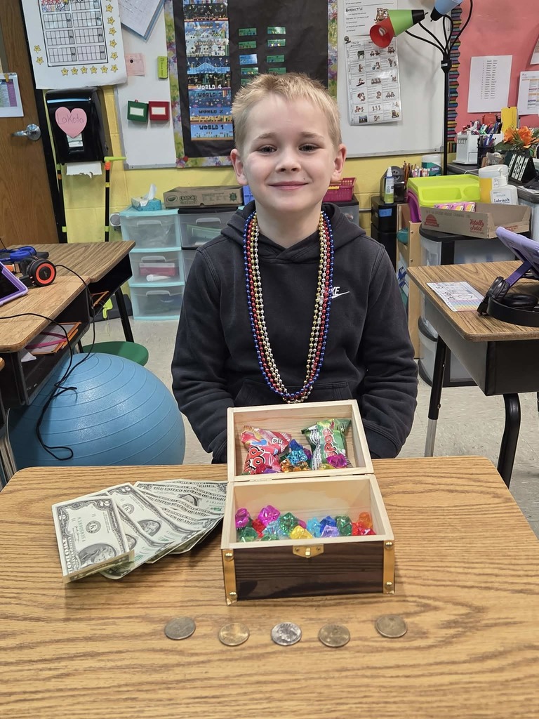 Photo of Jameson Ashley in his classroom with the treasure chest that he won along with cash, plastic jewelry and other small items in the chest.