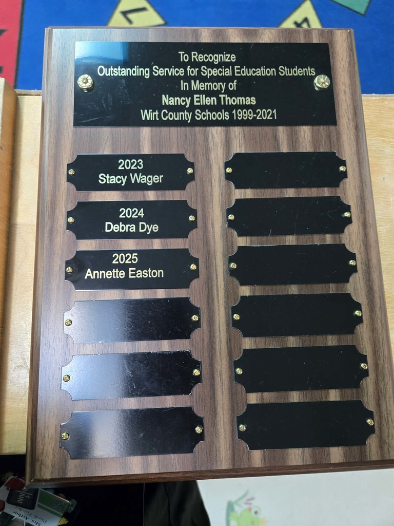 A close‑up image of a wooden recognition plaque. The top plate reads: “To Recognize Outstanding Service for Special Education Students in Memory of Nancy Ellen Thomas, Wirt County Schools 1999–2021.” Below it are engraved nameplates for the award recipients: “2023 Stacy Wager,” “2024 Debra Dye,” and “2025 Annette Easton,” with several blank spaces remaining for future honorees.