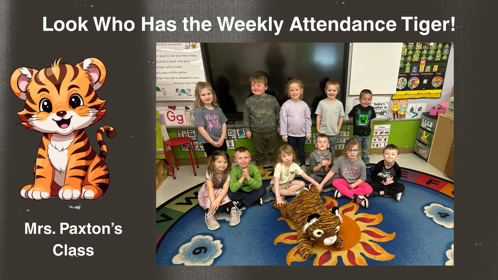 Graphic featuring a dark background with a smiling cartoon tiger on the left. Text reads “Look Who Has the Weekly Attendance Tiger!” and “Mrs. Paxton’s Class.” On the right, a classroom photo shows a group of elementary students seated and standing on a colorful rug around a stuffed tiger mascot. Classroom furniture, learning posters, and a whiteboard are visible in the background.