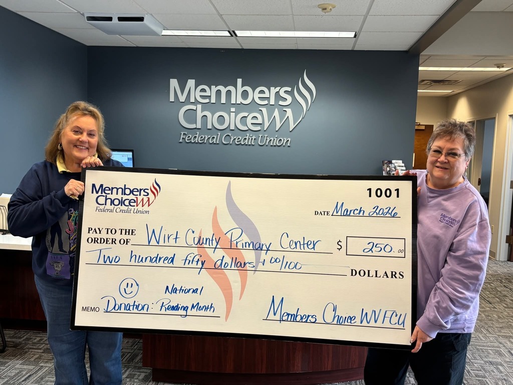 Two individuals stand inside a Members Choice WV Federal Credit Union office holding a large ceremonial check made out to Wirt County Primary Center for $250. The check is dated March 2026 and notes the donation is for National Reading Month. The credit union’s logo is visible on the wall behind them.