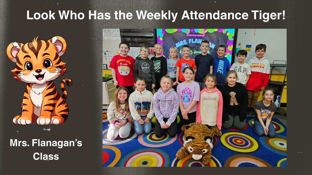 A classroom group photo with students arranged in two rows on a colorful circular rug. A stuffed tiger mascot lies on the floor in front of the group. Behind the students, a bulletin board with colorful decorations displays classroom materials. On the left side of the image is a graphic of a cartoon tiger and text that reads, ‘Look Who Has the Weekly Attendance Tiger! Mrs. Flanagan’s Class.’
