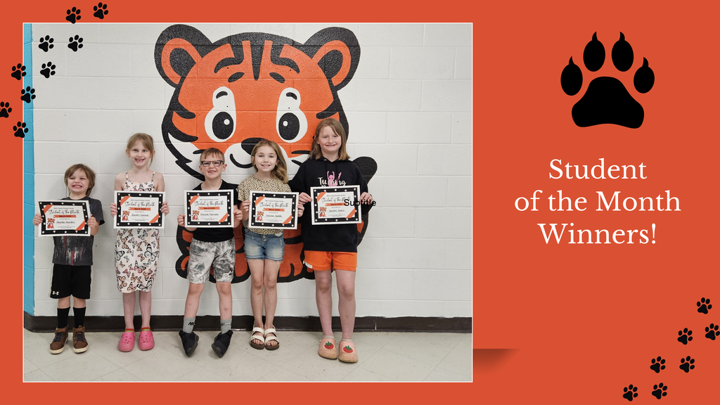 “Five elementary school students who are the March Students of the Month stand in a school hallway holding certificates. Behind them is a large painted tiger mascot on a white brick wall with the words ‘A Tiger Is Goal Oriented, Engaged, Respectful’ displayed above.”