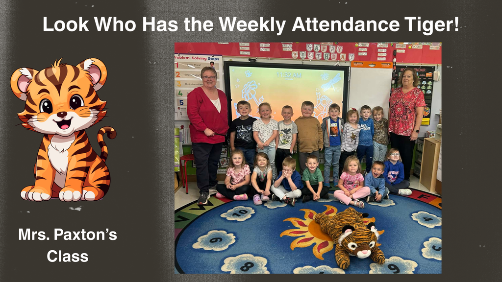 A classroom photo shows a group of young students seated on a colorful rug with two adults standing behind them. A plush tiger mascot lies on the rug in front of the students. To the left of the photo is a graphic with a cartoon tiger and the text, “Look Who Has the Weekly Attendance Tiger! Mrs. Paxton’s Class.” The classroom includes a smartboard, posters, and learning materials in the background.