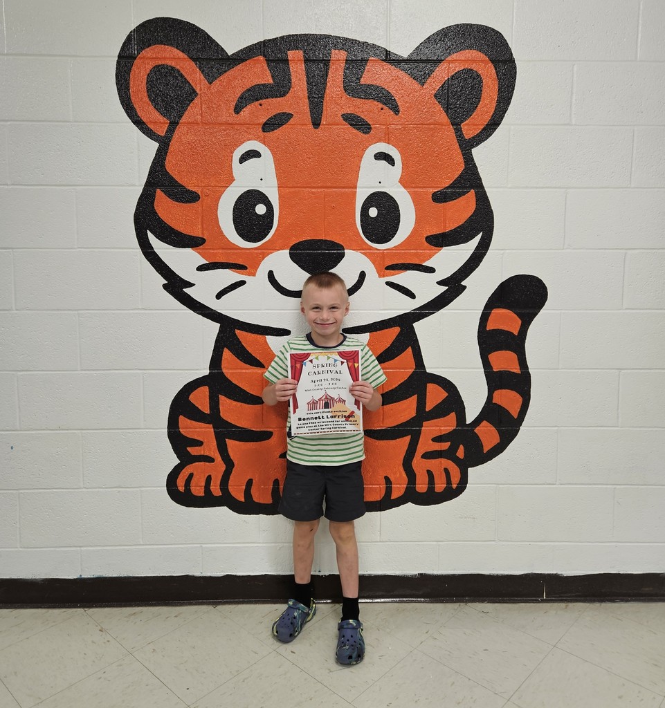 A student stands in a school hallway in front of a painted tiger mural, holding a Spring Carnival certificate that reads “Spring Carnival, April 24, 2025” with the name Bennett Larrison printed on it.