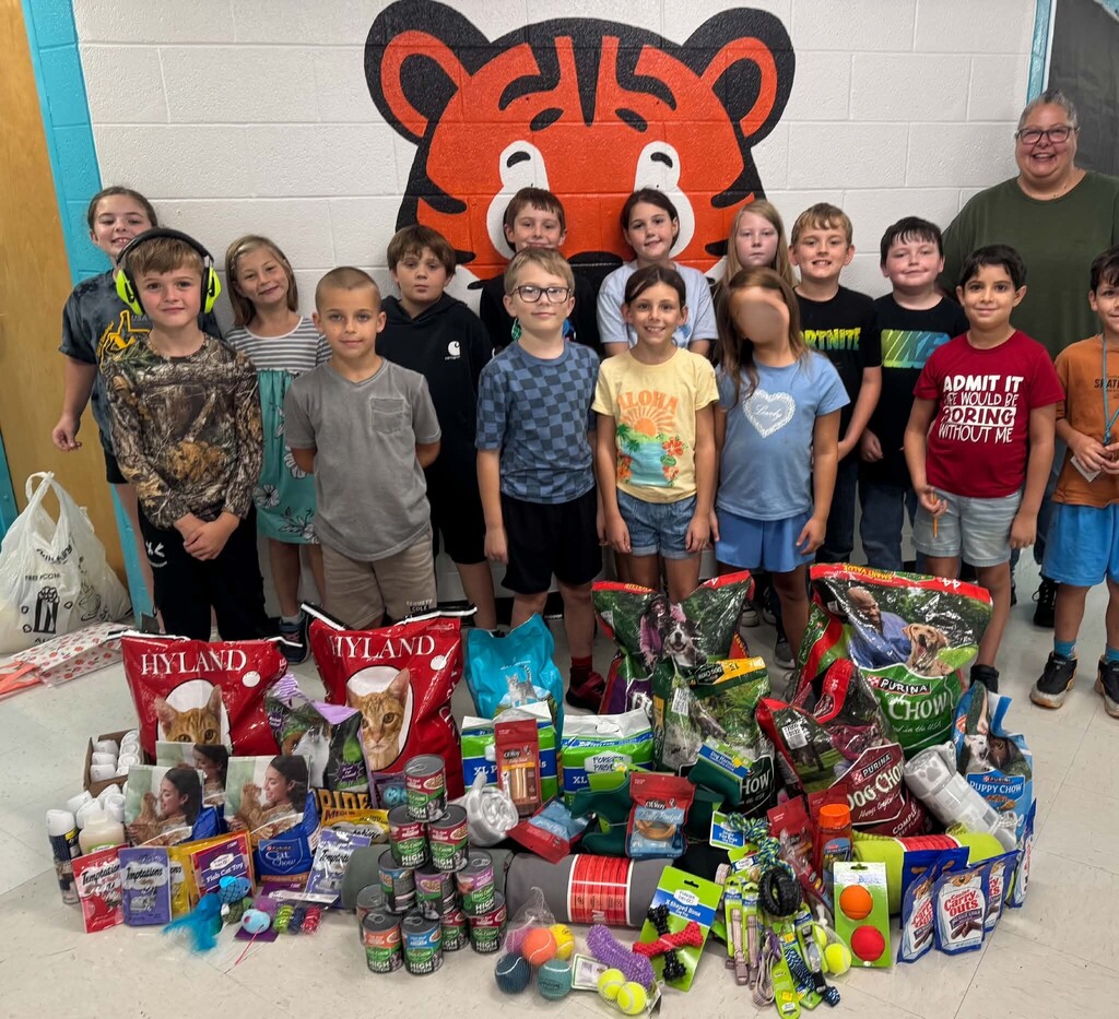 Image of Mrs. Sims' students standing in the hallway in front of the tiger cub with food donations for the animal shelter
