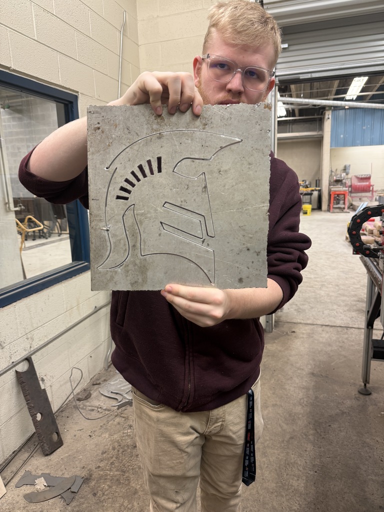 A student holds a fabricated metal sign