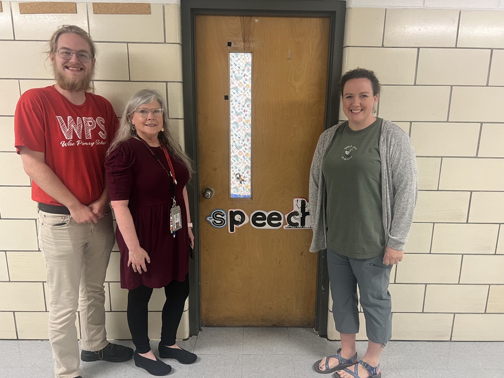 Three people in front of a door with the word "speech" written on it. Two women and one man.