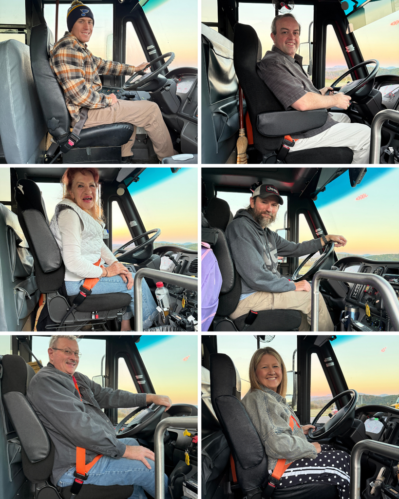 Four people in various positions seated inside a bus, wearing seat belts, with a view of the steering wheel.