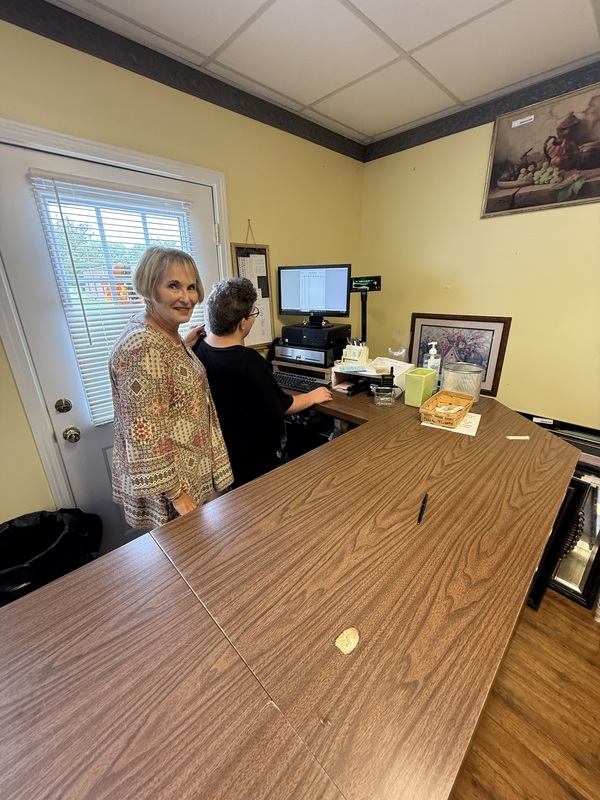 Pam stands behind a student checking out a customer