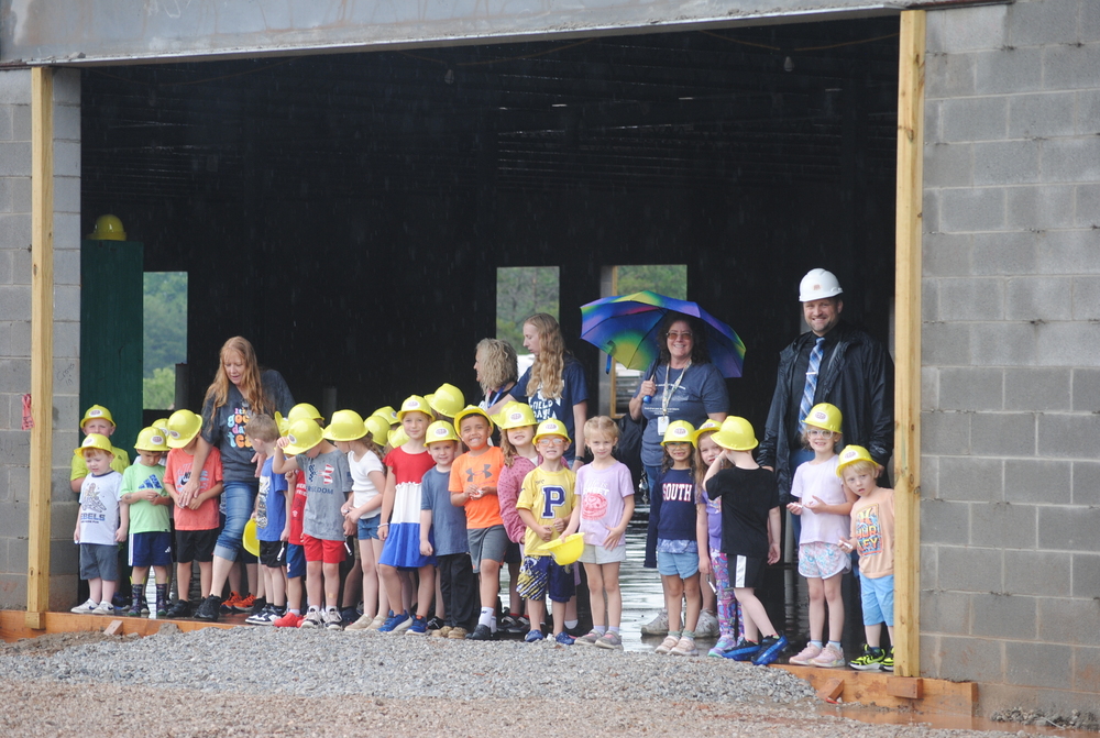 Pre Kindergarten students smiling at camera around block building
