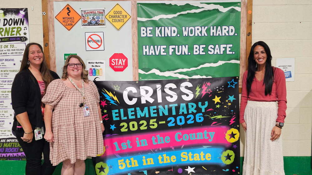 three teachers posing with a banner that says "Criss Elementary 2025-2026 - 1st in the County, 5th in the State"