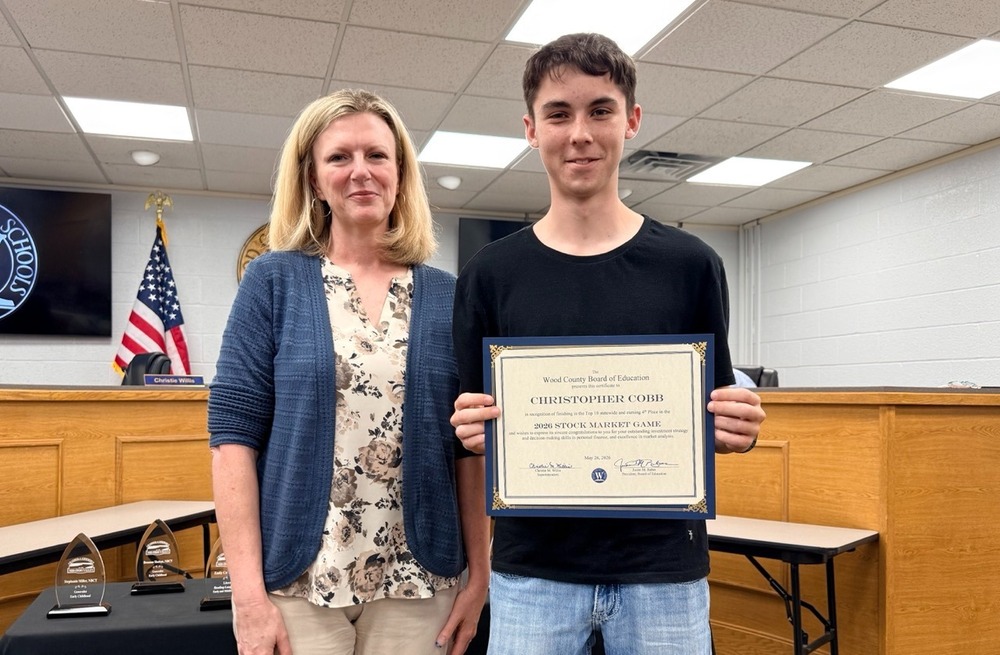 image of an adult female and a teenage student holding a certificate at a board of education meeting